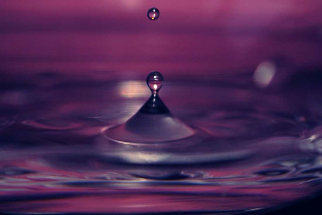 Paarse waterdruppel die in het water valt