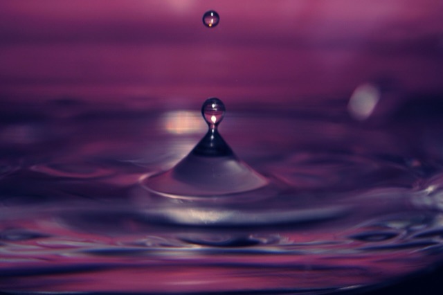 Paarse waterdruppel die in het water valt